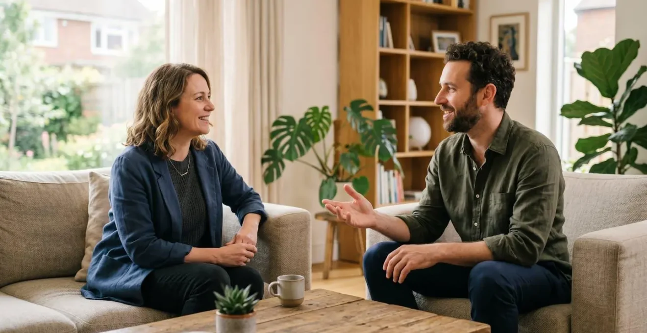 Deux personnes en discussion professionnelle bienveillante dans un salon moderne, l'une écoutant activement l'autre sans posture de domination